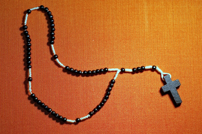 a close up of a rosary with a cross on it, by Carey Morris, inuit, [ overhead view ]!!, black jewellery, 1970s photo