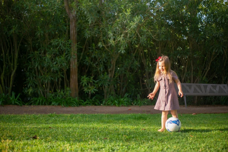 a little girl standing on top of a soccer ball, pexels, lush garden surroundings, well shaded, dribbling, 4yr old