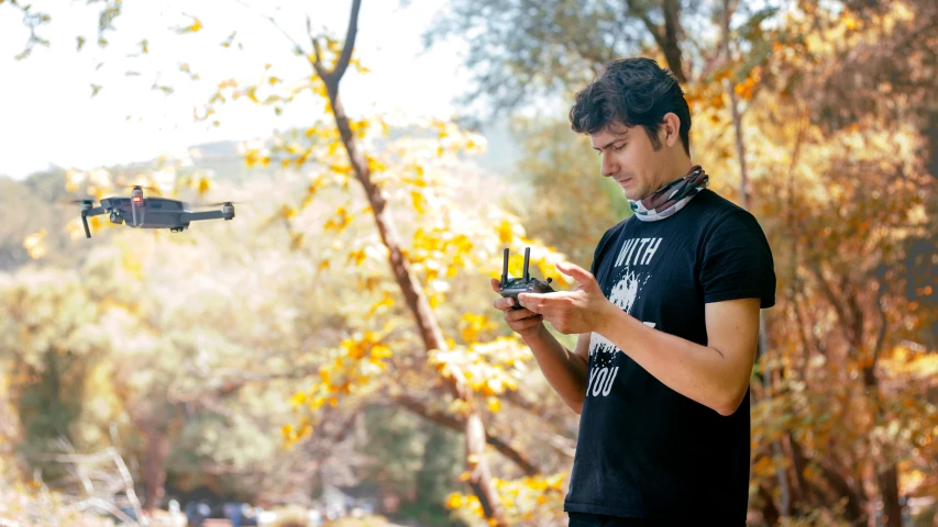 a man standing in the woods looking at his cell phone, unsplash, plein air, flying drones, avatar image, student, on set