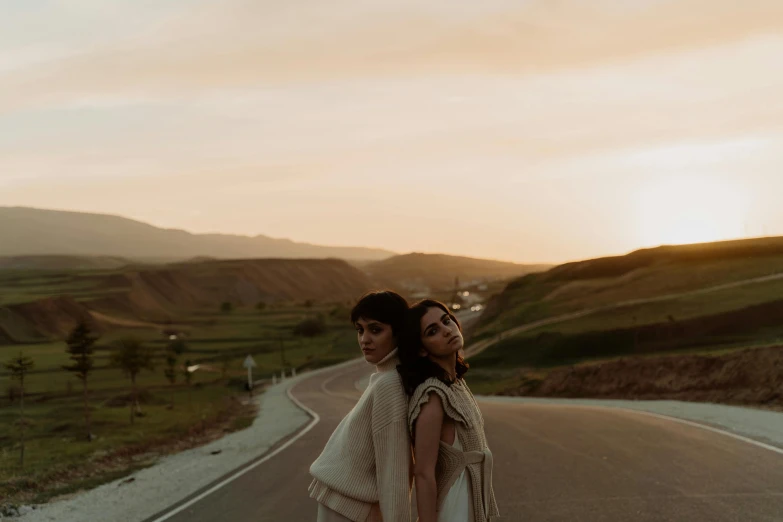 two women standing on the side of a road, trending on pexels, romanticism, kurdistan, white and gold robes, spring evening, lesbian