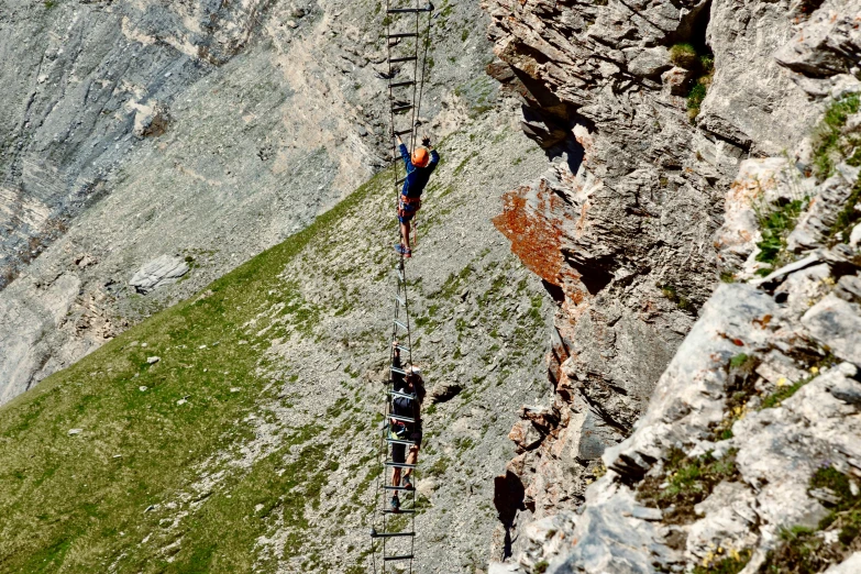 a group of people climbing up the side of a mountain, ladders, in the dolomites, profile image, cables hanging