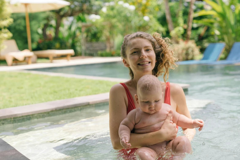 a woman holding a baby in a pool, bali, avatar image