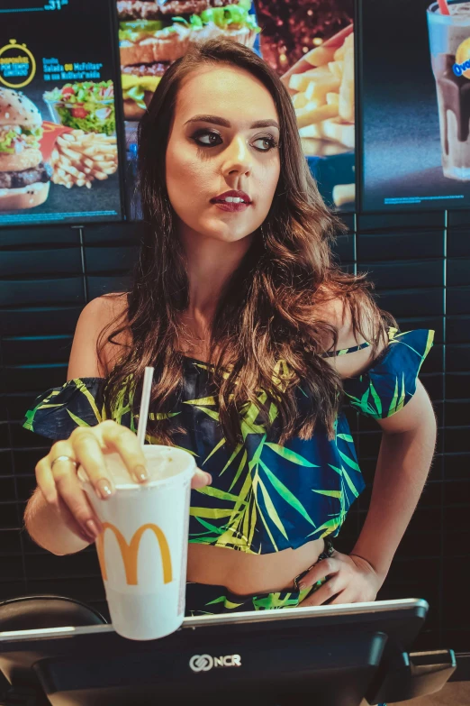 a woman sitting at a table with a drink in her hand, a colorized photo, inspired by Elsa Bleda, tumblr, blue mcdonalds, crop top, portrait demi rose, with hawaiian shirt