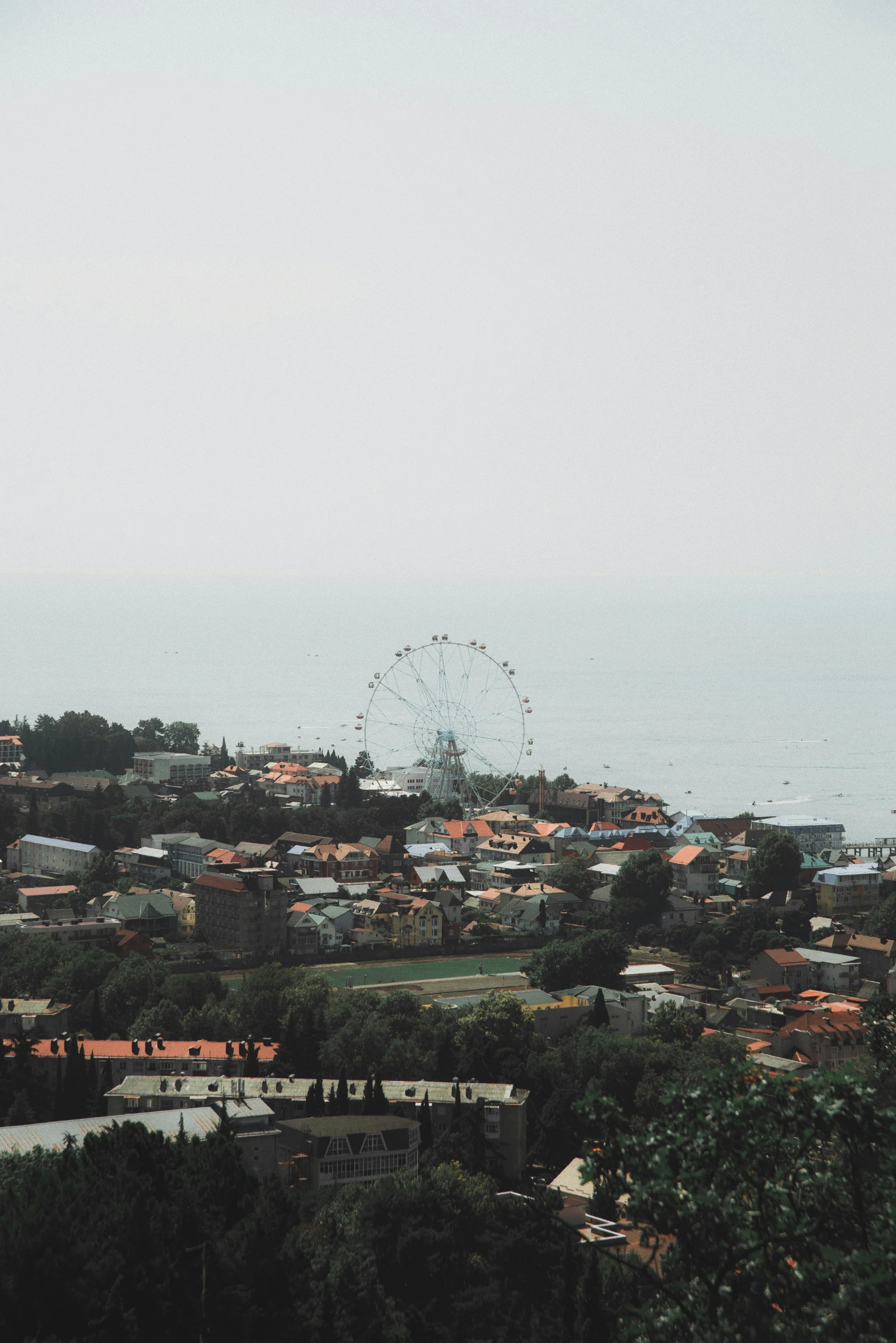 a view of a city with a ferris wheel in the background, black sea, on top of a hill, indonesia, null