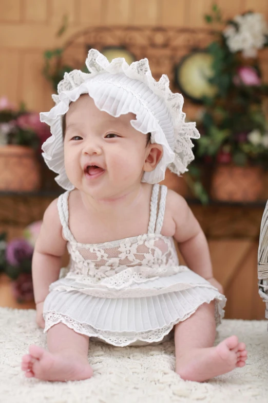 a baby sitting on top of a white rug, inspired by Margaret Brundage, shutterstock contest winner, renaissance, young asian girl, dressed in a frilly ((lace)), cute hats, excited