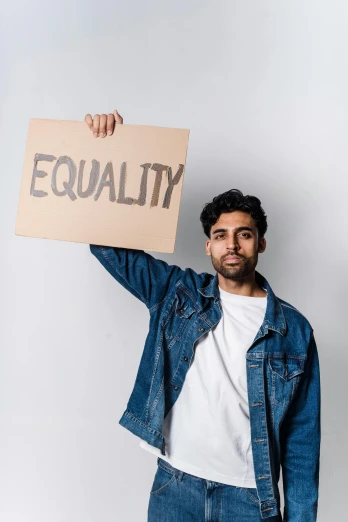 a man holding a sign that says equality, an album cover, trending on pexels, renaissance, indian, beautiful young man, thumbnail, brown