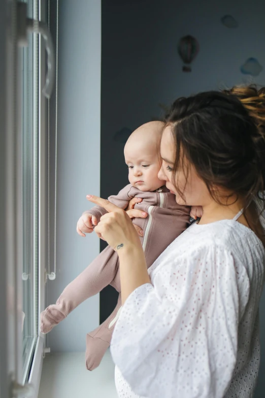 a woman holding a baby looking out a window, profile image, day time, maintenance, brunette