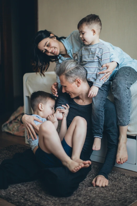 a family sitting on a couch in a living room, by Adam Marczyński, pexels contest winner, incoherents, hugging his knees, non-binary, soft grey and blue natural light, thumbnail