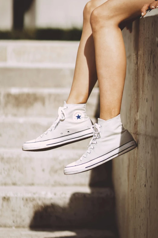a person that is sitting on some steps, converse, white and silver, zoomed in, tall thin