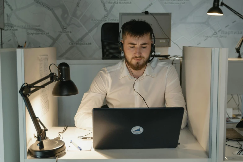 a man sitting at a desk with a laptop and headphones, by Adam Marczyński, hurufiyya, in an call centre office, avatar image, unedited, cinematic image