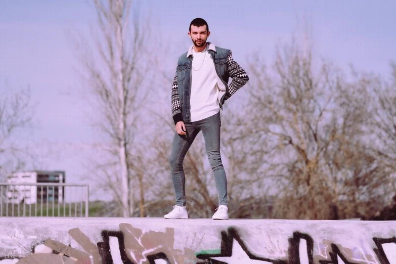 a man standing on top of a cement wall, an album cover, by Tamas Galambos, pexels contest winner, ( ( ( wearing jeans ) ) ), artem chebokha, still from a music video, avatar image