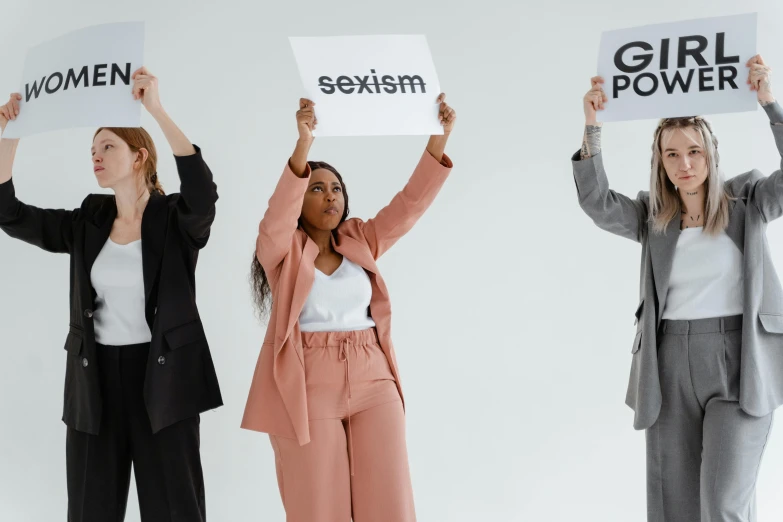 a group of women holding up signs in the air, trending on pexels, sexuell, 3 - piece, grayish, office clothes