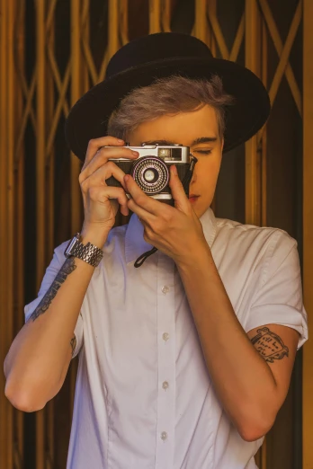 a man taking a picture with a camera, inspired by Elsa Bleda, trending on pexels, photorealism, short platinum hair tomboy, wearing a tophat, justin bieber, vintage color photo