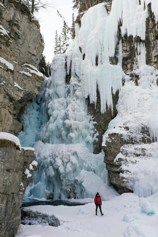 a person standing in front of a frozen waterfall, banff national park, panorama, steep cliffs, 2019 trending photo