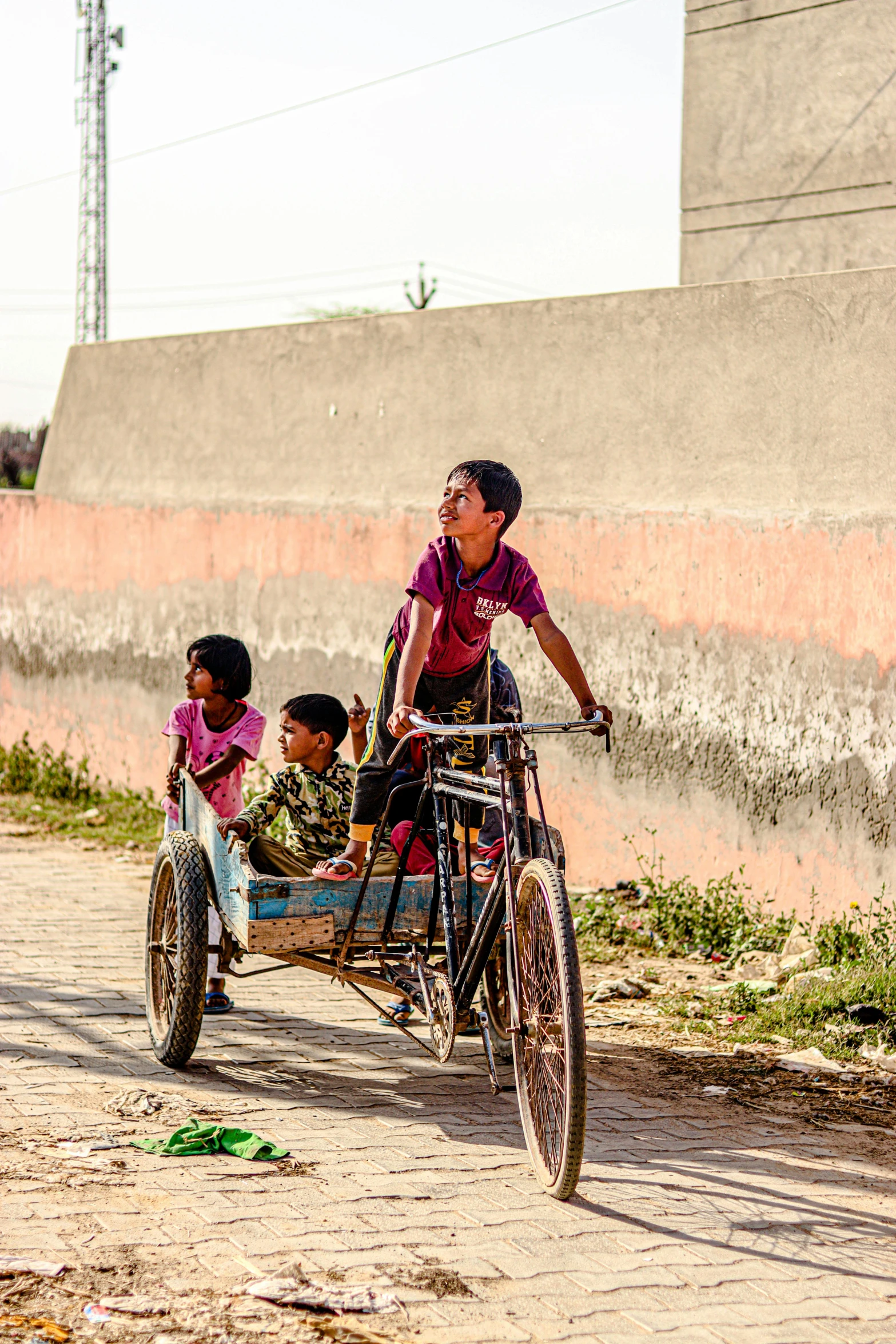 a group of children riding on the back of a bike, by Rajesh Soni, pexels contest winner, on a village, cart, baotou china, sunny day time
