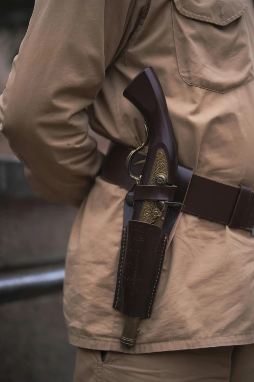 a close up of a person holding a gun, renaissance, wide belt scabbard, carrying survival gear, zulu, brown