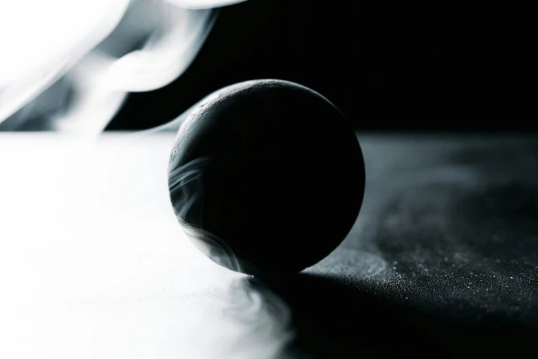 a black and white photo of a ball on a table, soft smoke, ashford black marble, dynamic angled shot, half turned around