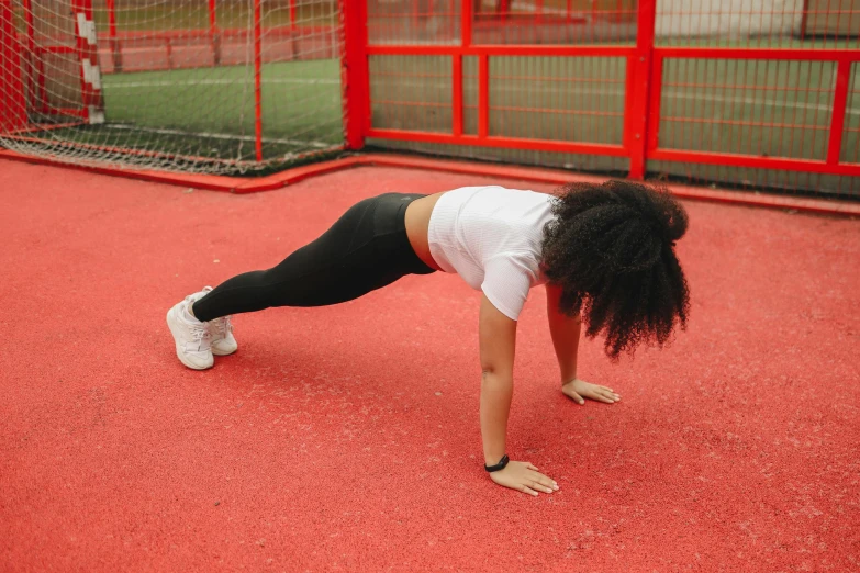 a woman doing push ups on a red surface, pexels contest winner, outside on the ground, background image, thumbnail, low quality photo