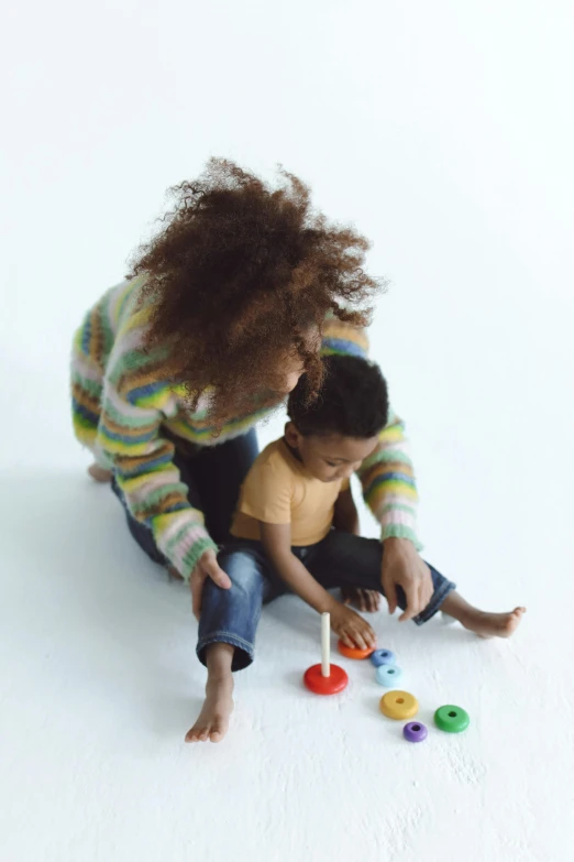 a woman playing with a child on the floor, visual art, children playing with pogs, rhythm & hues, lgbtq, essence