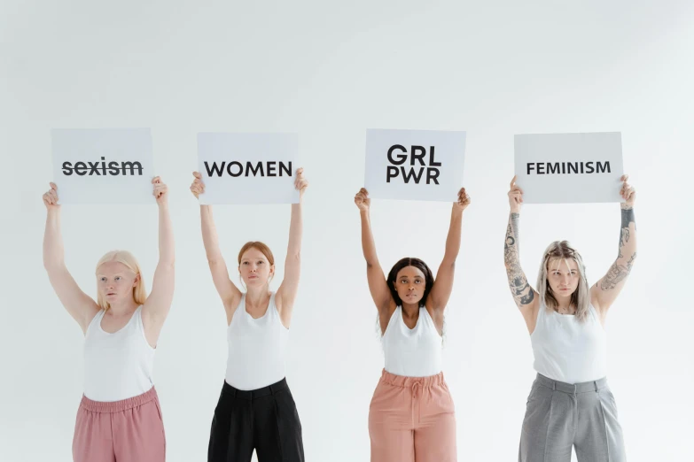 a group of four women holding up signs, by Arabella Rankin, trending on pexels, !female, grit, background image, powerfull