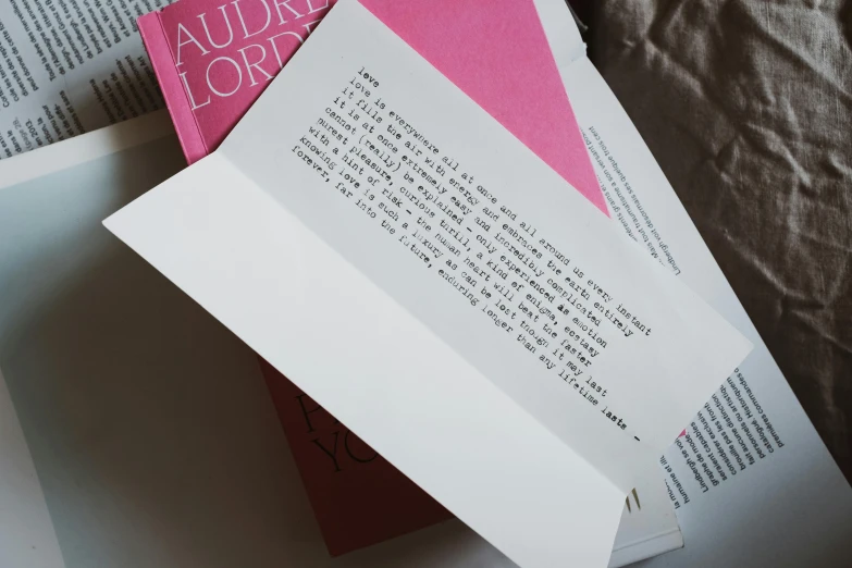 a pile of books sitting on top of a bed, inspired by Louise Bourgeois, tumblr contest winner, letterism, invitation card, close up front view, pink, audrey hepburn
