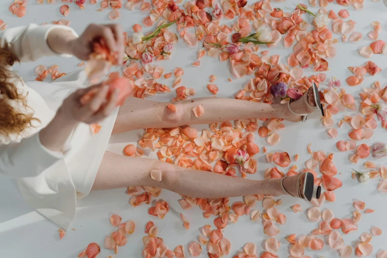 a woman sitting on a bed covered in petals, trending on pexels, aestheticism, oranges floating in the water, woman holding another woman, low quality photo, painted nails