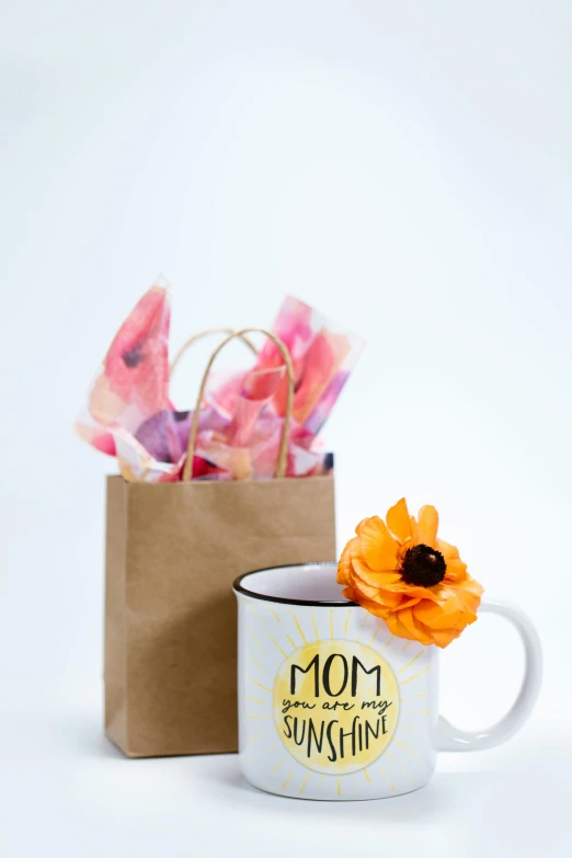 a white coffee mug sitting next to a brown paper bag, your mom, poppy, sun overhead, set against a white background