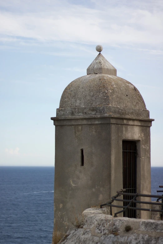 a building sitting on top of a cliff next to the ocean, inspired by Julio Larraz, renaissance, neoclassical tower with dome, puerto rico, ventilation shafts, 1759