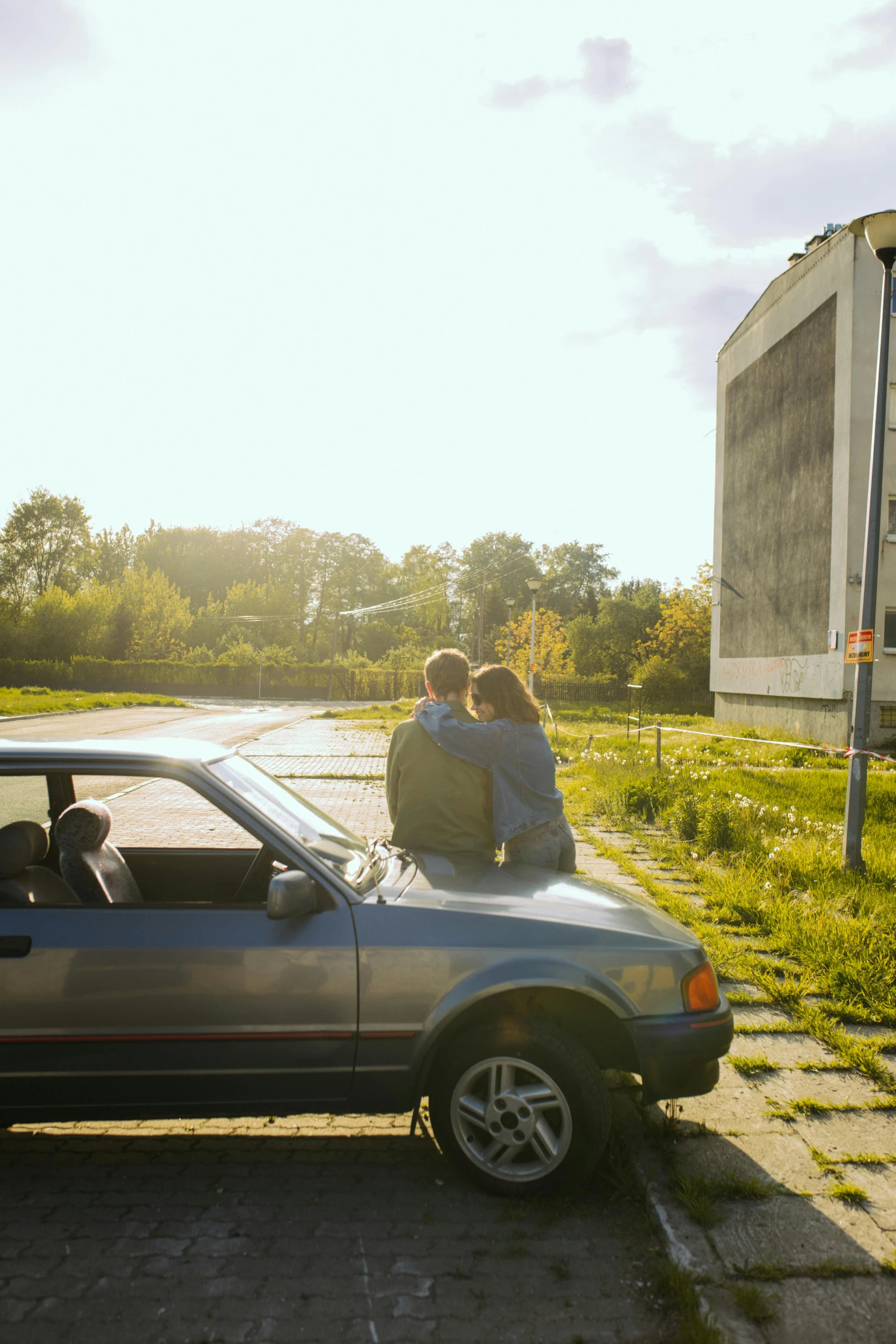 a couple of people sitting on top of a car, inspired by Nan Goldin, unsplash, romanticism, cinemascope panorama, drive in movie theater, square, beautiful daylight