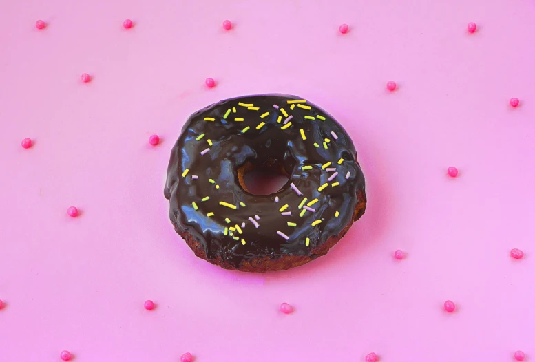 a chocolate donut with sprinkles on a pink surface, by Juliette Wytsman, pexels, 🦩🪐🐞👩🏻🦳, deep black, banana, black