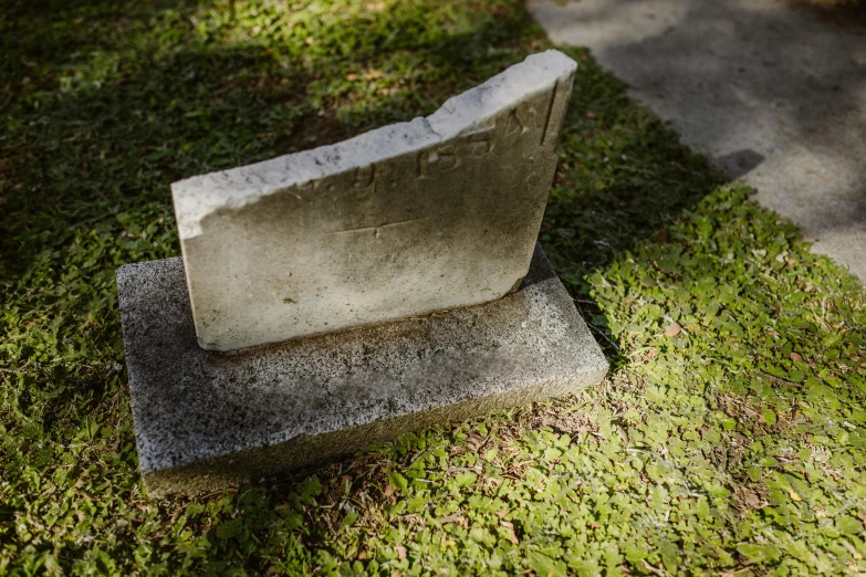 a stone bench sitting on top of a lush green field, a marble sculpture, inspired by Ian Hamilton Finlay, unsplash, concrete art, decaying dappled sunlight, parce sepulto, with a square, mossy ground