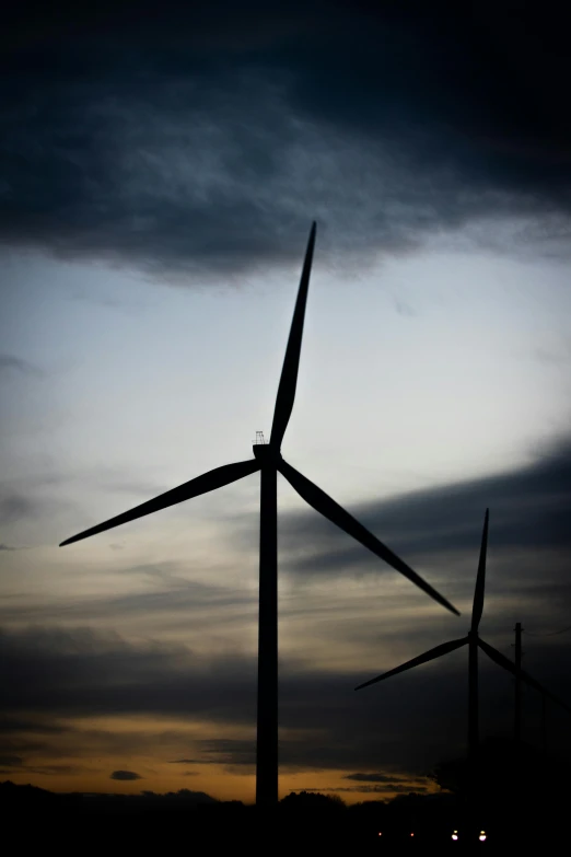 a couple of wind turbines sitting on top of a field, a portrait, by Joe Stefanelli, photographed for reuters, silhouetted, grey, up close