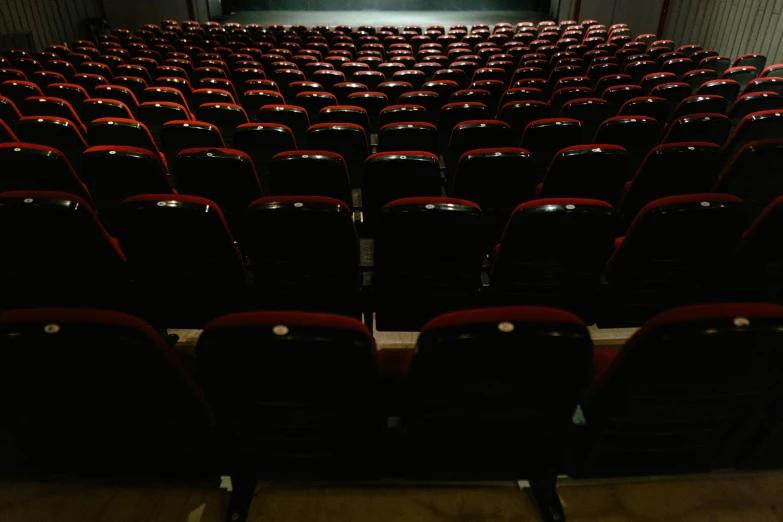 a large auditorium with rows of red seats, a portrait, by Everett Warner, pexels, movie poster with no text, with a black background, instagram picture, contain