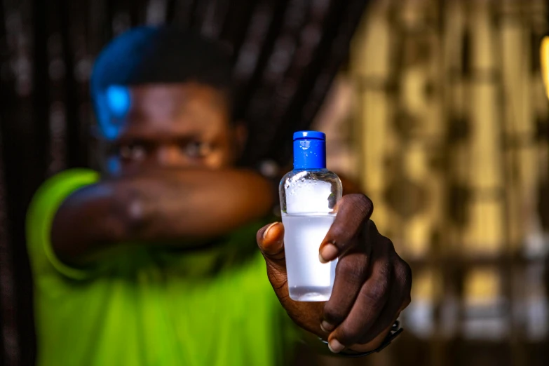 a man holding a bottle of water in his hand, a portrait, by Daniel Lieske, pexels contest winner, afro tech, glowing oil, official product photo, made of plastic