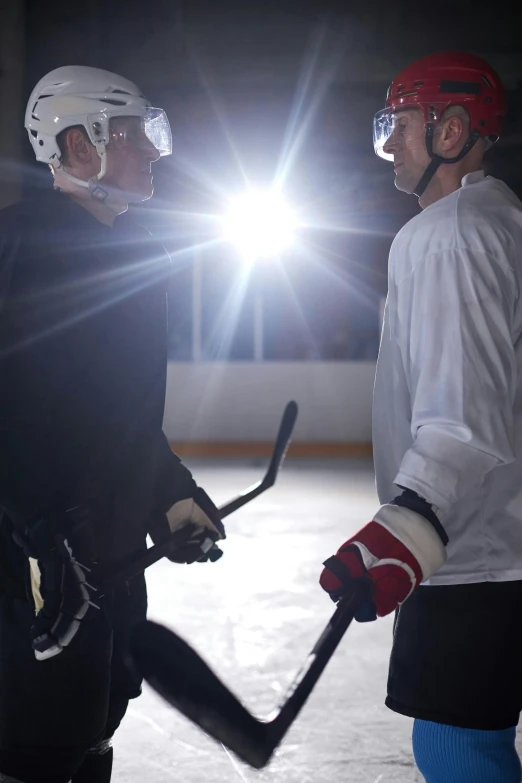 a couple of men standing next to each other on top of a ice rink, sparring, under light, no - text no - logo, nhl