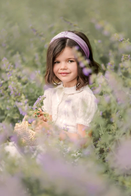 a little girl sitting in a field of purple flowers, press shot, ribbons and flowers, portrait image