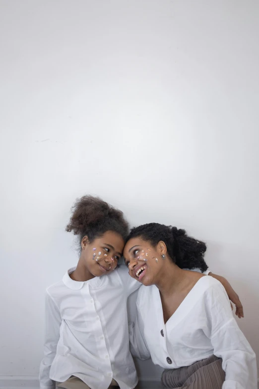 a couple of women sitting next to each other, an album cover, by Nina Hamnett, trending on unsplash, caring fatherly wide forehead, in white room, photographed for reuters, aida muluneh