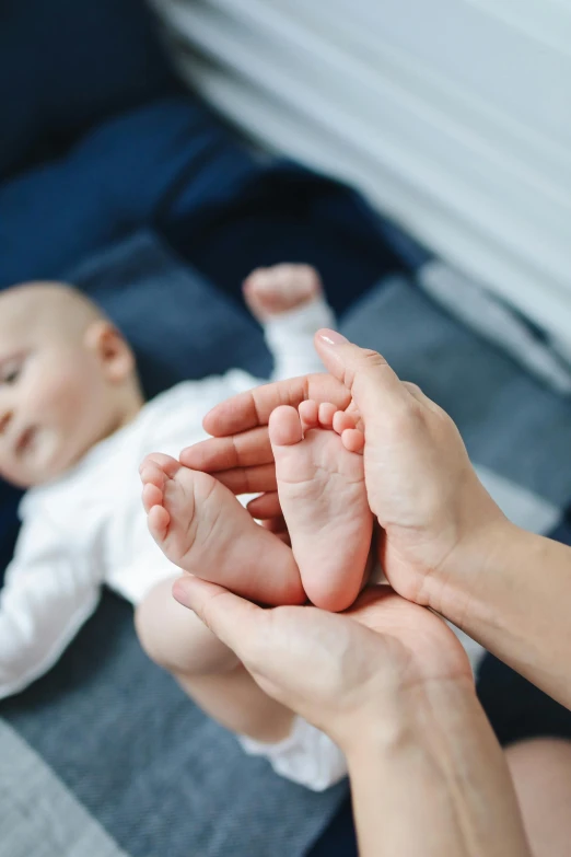 a close up of a person holding a baby's foot, incoherents, in the center of the image, soft pads, looking happy, professional image