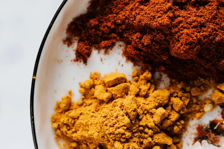 a white plate topped with different types of spices, by Carey Morris, red and golden color details, powder, thumbnail, up close image