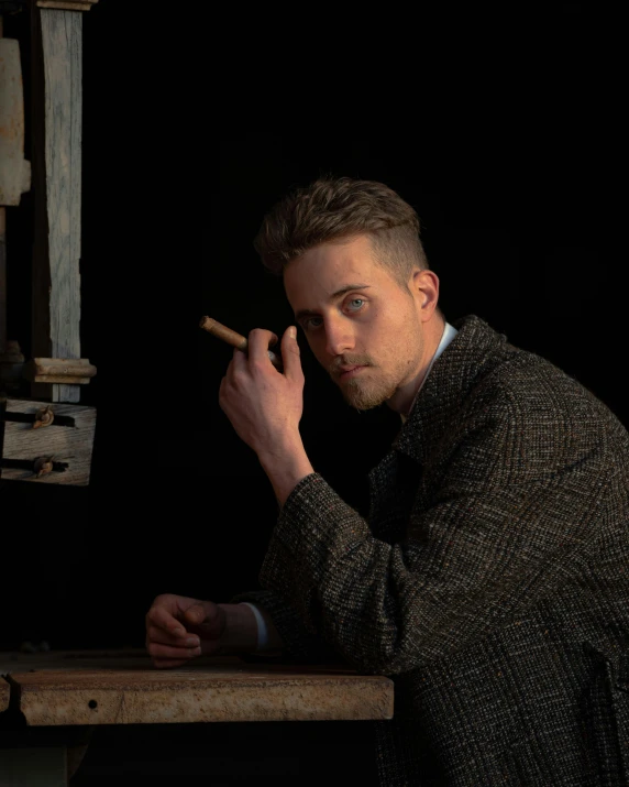 a man sitting at a table smoking a cigarette, a character portrait, inspired by Peter Rockwell, pexels contest winner, ryan gosling, danny fox and hilma af klint, androgynous person, holding a wood piece