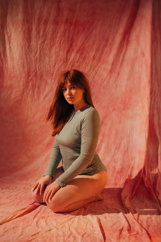 a woman sitting on top of a pink sheet, an album cover, inspired by Elsa Bleda, renaissance, thick thighs, she is redhead, wearing tight shirt, soft grey and red natural light