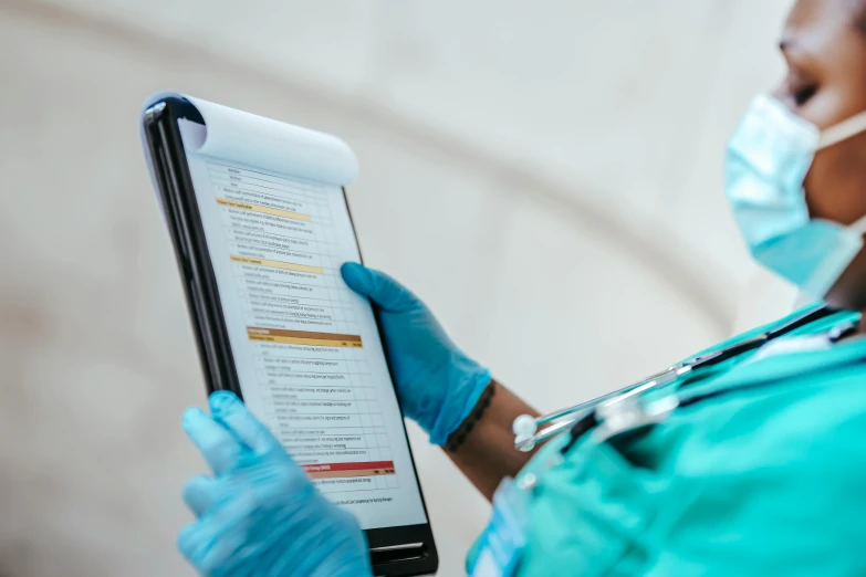 a woman in a blue scrub suit holding a clipboard, pexels, happening, large screen, diagnostics, thumbnail, up-close