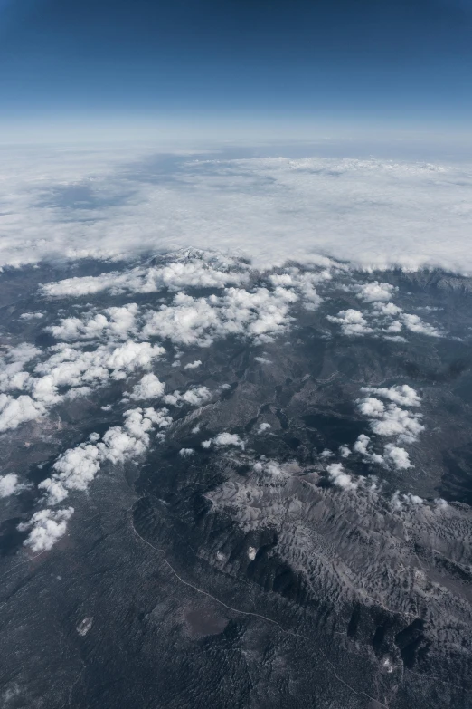 a view of mountains and clouds from an airplane, by Daren Bader, trending on unsplash, baroque, looking down at a massive crater, grey, exoplanet landscape, central california