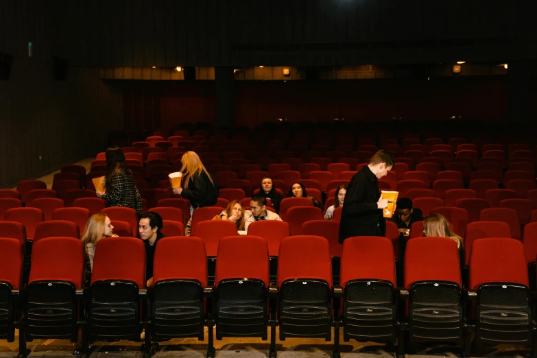 a group of people sitting in rows of red chairs, movies, jovana rikalo, high quality photo, movie footage