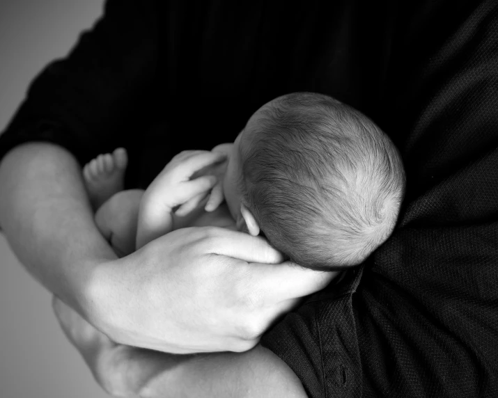 a man holding a baby in his arms, a black and white photo, by Caroline Mytinger, pixabay, portrait image, closeup photo, scientific photo, photorealistic photo