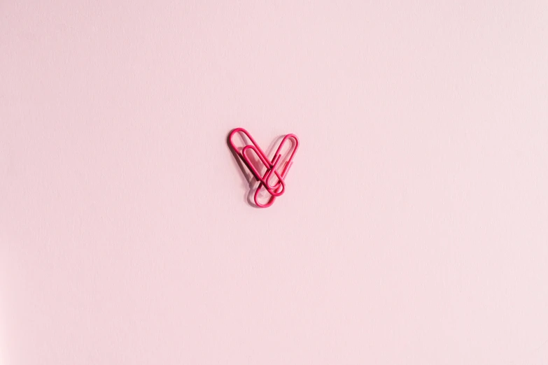 a paper clip in the shape of a heart on a pink background, by Emma Andijewska, pexels, unsplash photo contest winner, shot on sony a 7 iii, mid air shot, maths