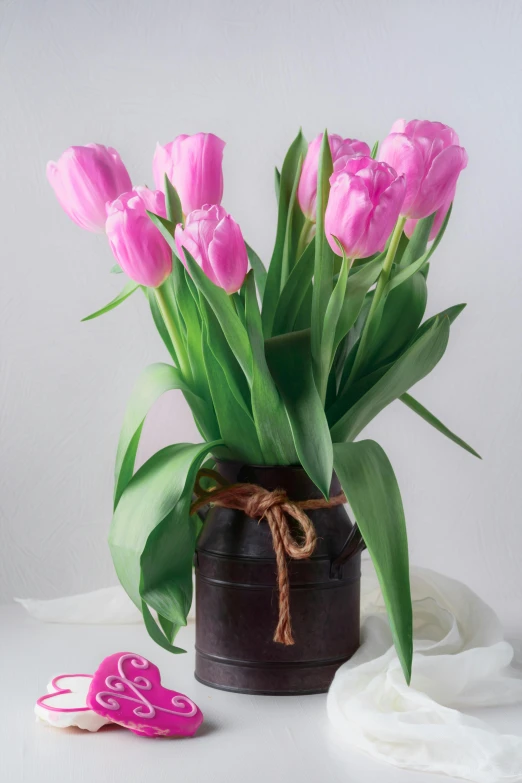 a vase filled with pink tulips next to a heart shaped cookie, light pink mist, full product shot, seasonal, flowy