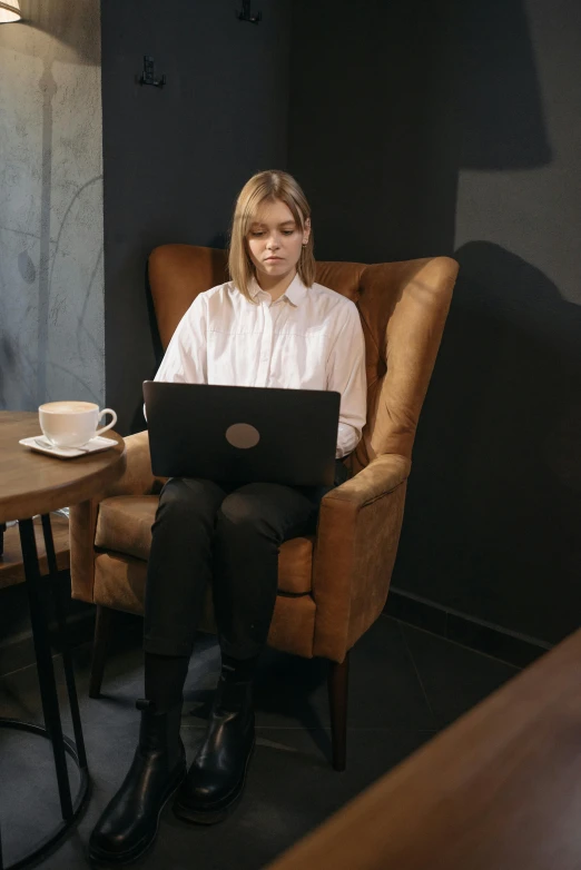 a woman sitting in a chair with a laptop, by Adam Marczyński, trending on pexels, renaissance, wearing a dark shirt and jeans, customers, greta thunberg, girl in suit