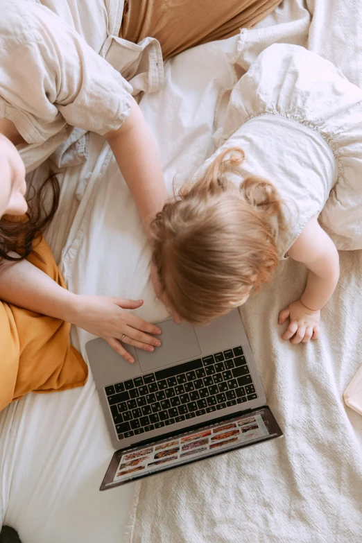 a woman and child laying on a bed with a laptop, pexels contest winner, head down, developers, thumbnail, lower quality