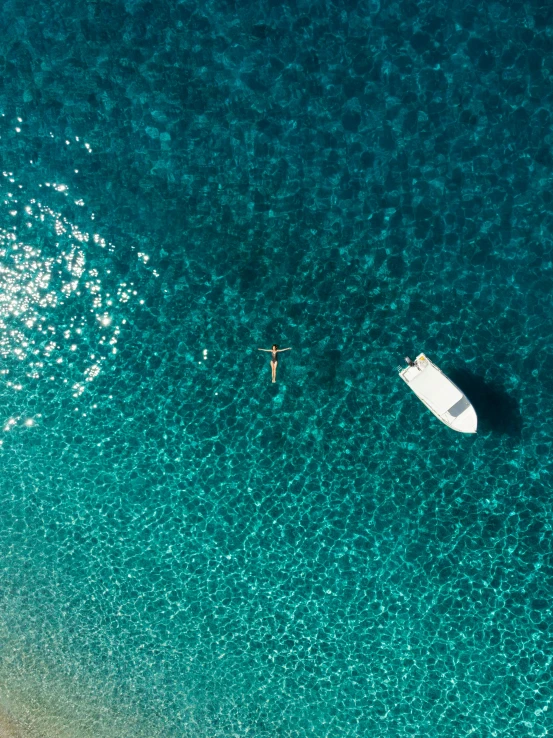 a couple of boats floating on top of a body of water, the ocean, from above, single figure, the beach